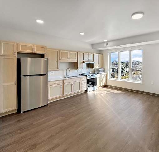 A kitchen with wooden cabinets and a stainless steel refrigerator.
