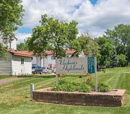 A sign for Vashon's Highlands is in the foreground of a grassy area.