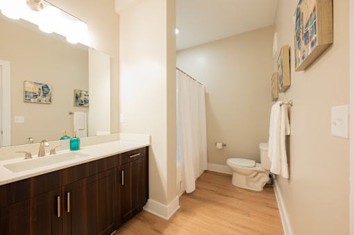 A bathroom with a white sink and brown cabinets.