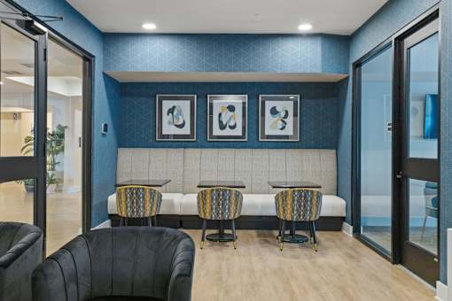 A room with a blue wall and a bench with three chairs.