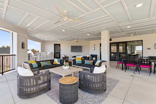 A modern outdoor living space with a white ceiling fan and a black and white striped rug.