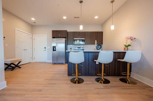 A kitchen with a bar area and white chairs.