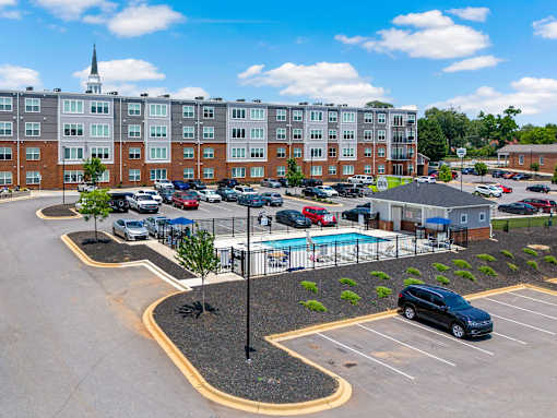 A parking lot with a pool and a building in the background.