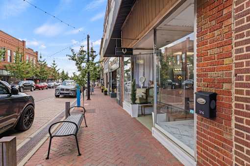 A brick sidewalk leads to a storefront with a black mailbox on the right.