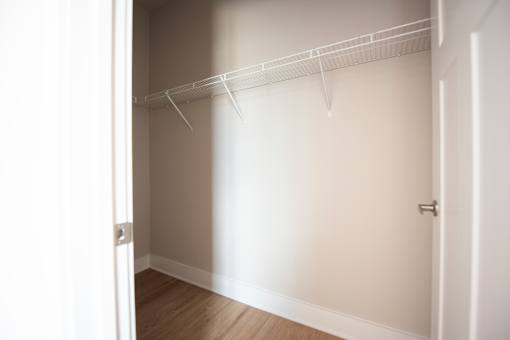 A white closet with a door and a shelf.