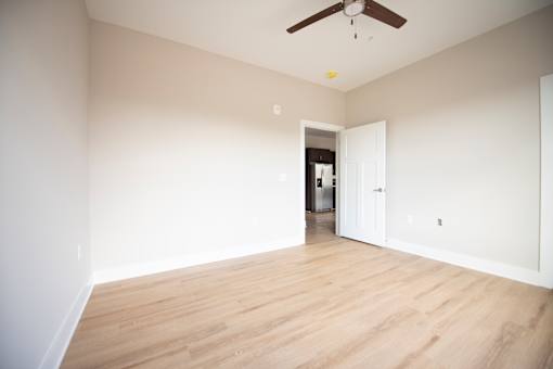A room with a ceiling fan and wooden flooring.