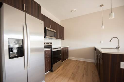 A kitchen with a refrigerator, microwave, oven, and sink.