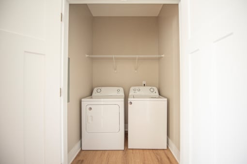 Two white washing machines in a small laundry room.
