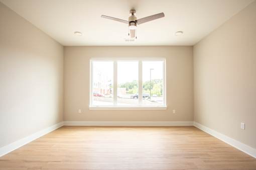 A room with a ceiling fan and a large window.