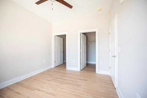A room with a ceiling fan and three open doors.