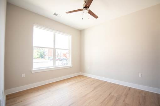 Empty room with a window and a ceiling fan.