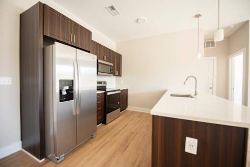 A modern kitchen with a stainless steel refrigerator and wooden cabinets.