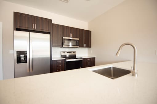 A kitchen with a sink, refrigerator, and microwave.