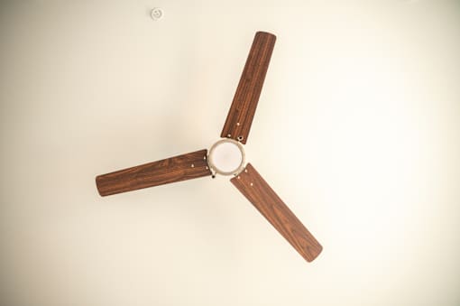 A ceiling fan with wooden blades and a white ceiling.