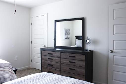 A bedroom with a bed, dresser, and mirror.