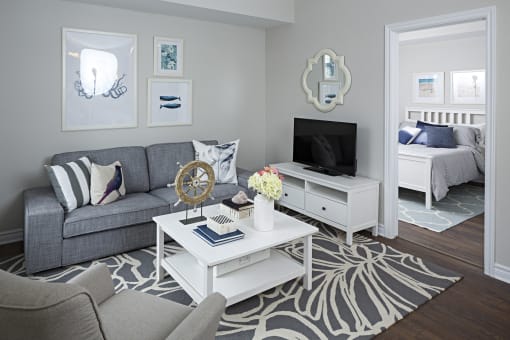 a living room with a gray couch and a white coffee table and a television
