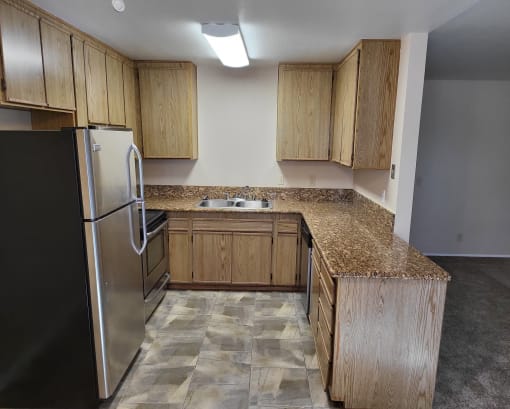 an empty kitchen with granite counter tops and wooden cabinets