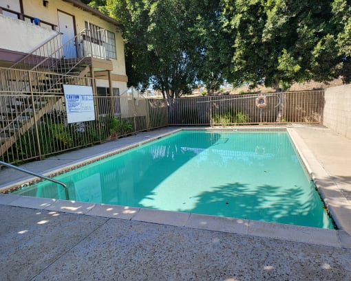 a swimming pool in front of a building with a fence