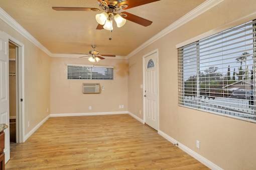 an empty living room with a ceiling fan and a window