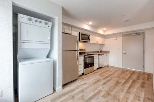 A white fridge and oven in a kitchen with wooden flooring.