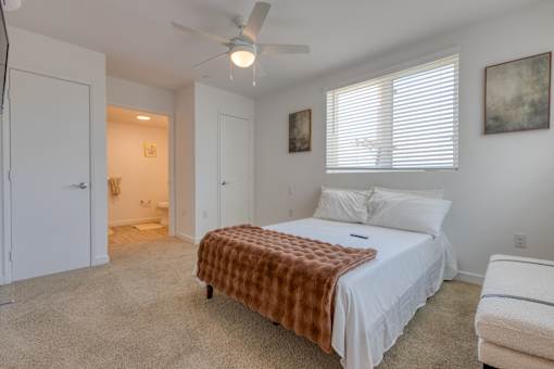 A bedroom with a bed covered in a brown blanket and a ceiling fan.