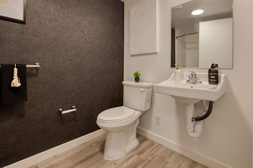 A bathroom with a toilet, sink, and mirror.