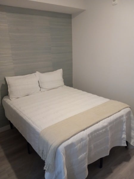 A bed with a white cover and two pillows.