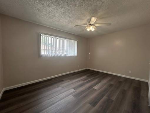 A room with a ceiling fan and a window with blinds.