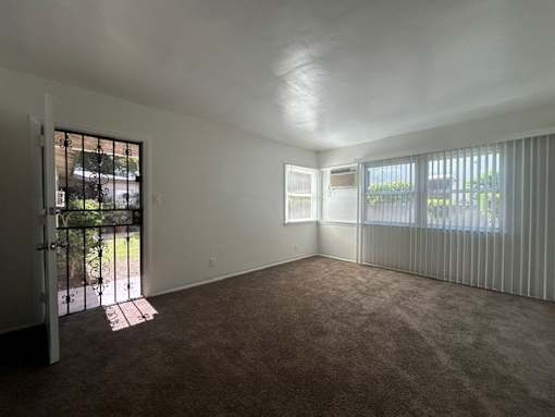 A room with a carpeted floor and a sliding glass door.