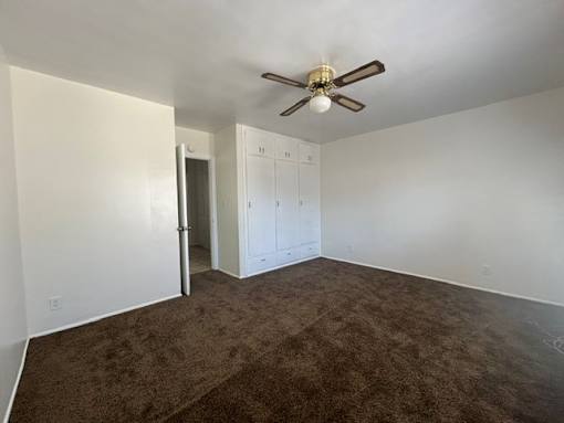 A room with a ceiling fan and carpeted floor.