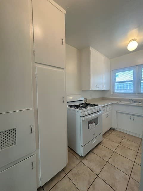 A kitchen with a white refrigerator, stove, and cabinets.