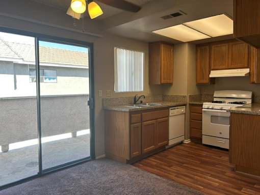 A kitchen with wooden cabinets and a white stove top oven.