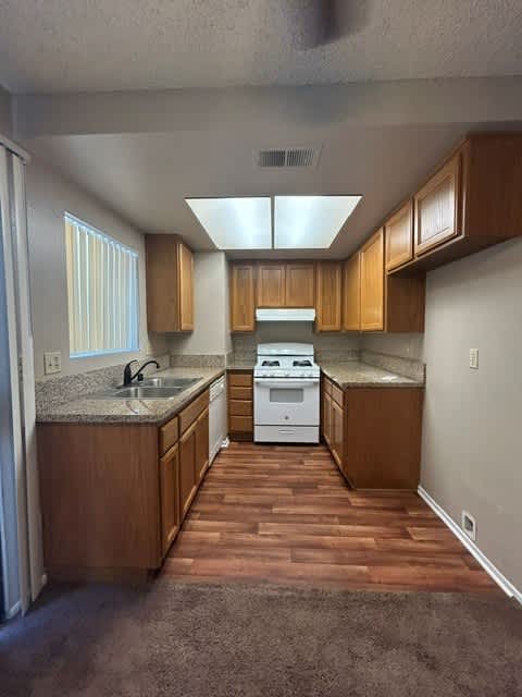 A kitchen with wooden cabinets and a white stove top oven.