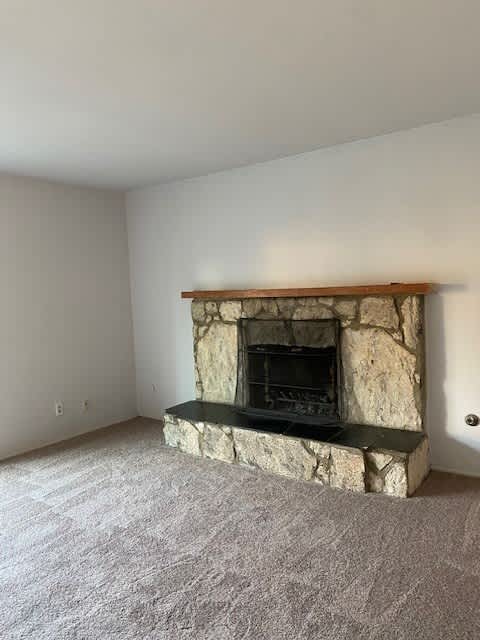an empty living room with a stone fireplace