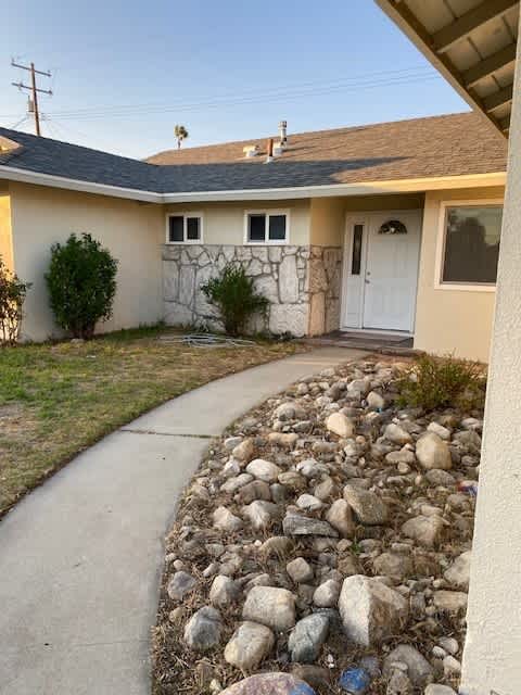 a house with a sidewalk and rocks in front of it