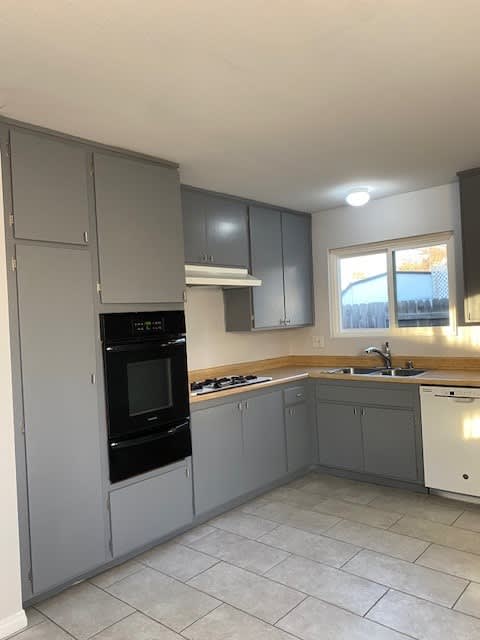 a kitchen with gray cabinets and a black oven