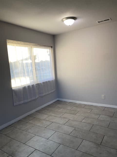 an empty room with a window and a tiled floor