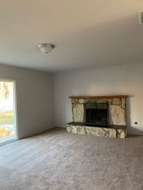 an empty living room with a stone fireplace