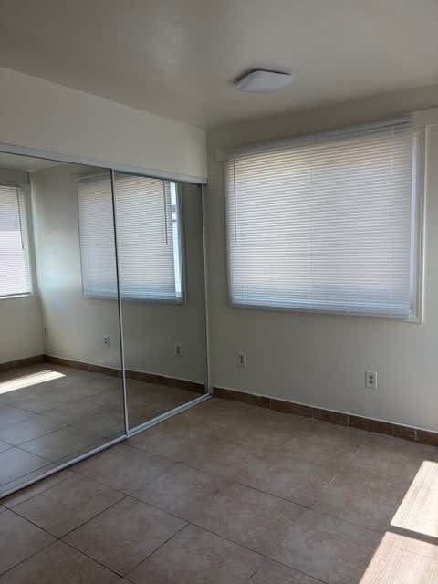 A room with a sliding glass door and a window with blinds.