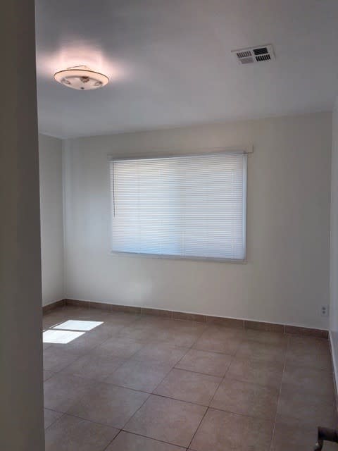 A room with a window covered by white blinds and a light on the ceiling.