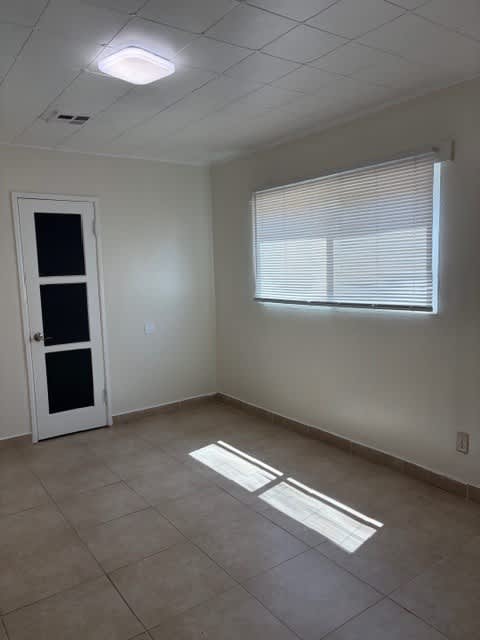 A room with a door, window, and tiled floor.
