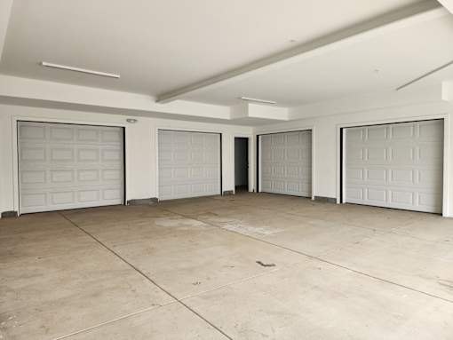 A spacious garage with four doors and a concrete floor.