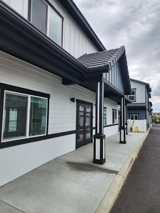 A white building with black trim and a black awning.