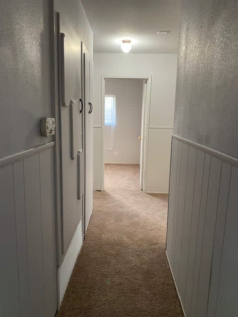 a hallway with a white door and a carpeted floor