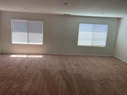 an empty living room with wood floors and two windows