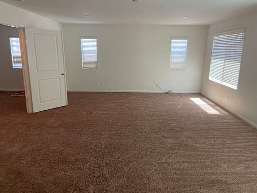 an empty living room with carpet and a white door