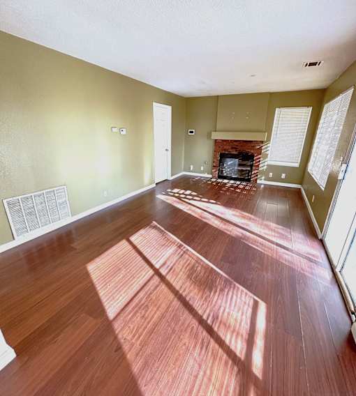 A room with a fireplace and wood flooring.