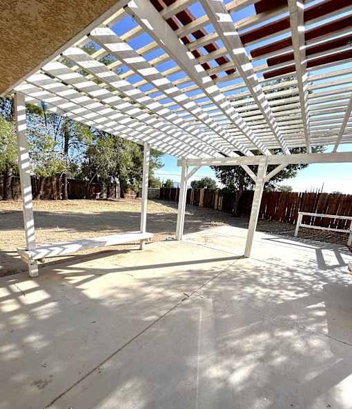 A white pergola with a wooden roof and pillars.