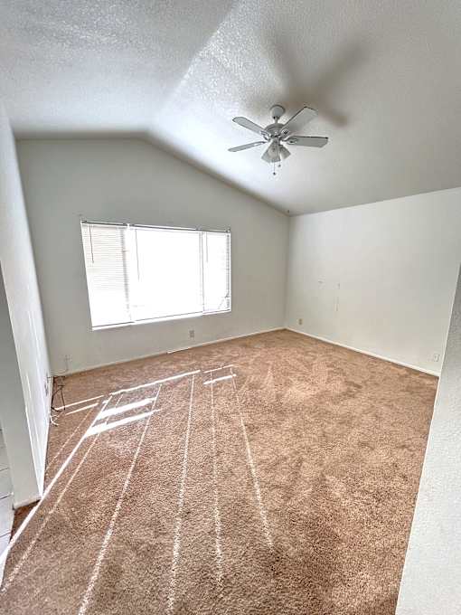 A room with a ceiling fan and a window with blinds.