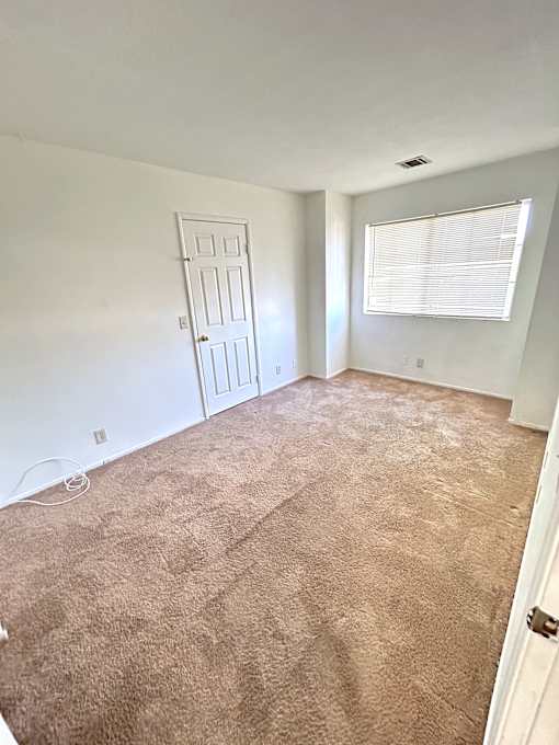 A room with a brown carpet and a white door.